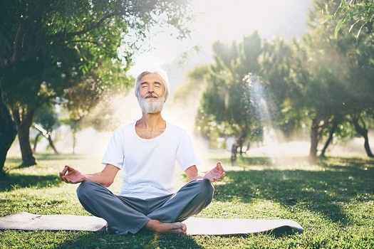 Senior man doing meditation in park