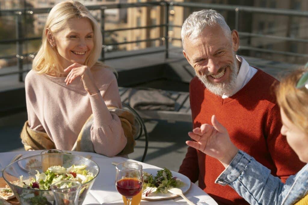 Older couple laughing with friends on a sunny patio